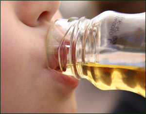 The hard-core apple juice liver cleansing diet: woman drinking apple juice from a bottle.